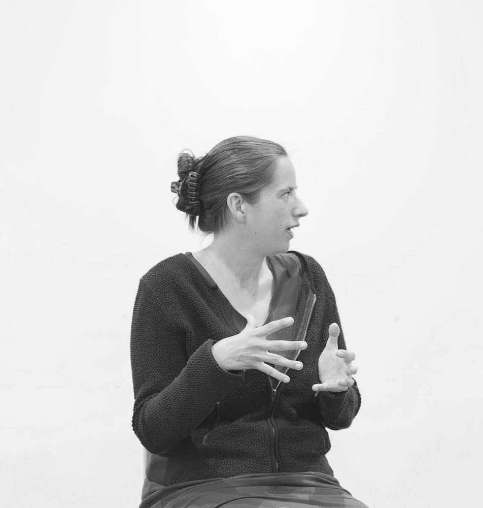 Melanie Suzanne Wilson speaking and sitting black and white